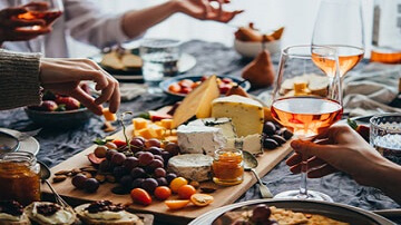 Planche de fromages et raisin et personnes buvant du rosé