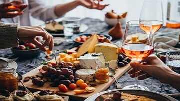 Planche de fromages et raisin et personnes buvant du rosé