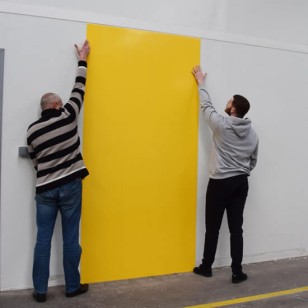 Personnes posant une plaque de PVC jauen comme revêtement mural dans une cuisine professionnelle