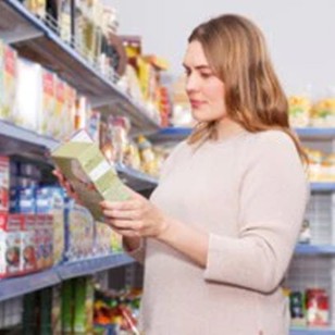 Femme lisant l'étiquette d'un produit dans un supermarché